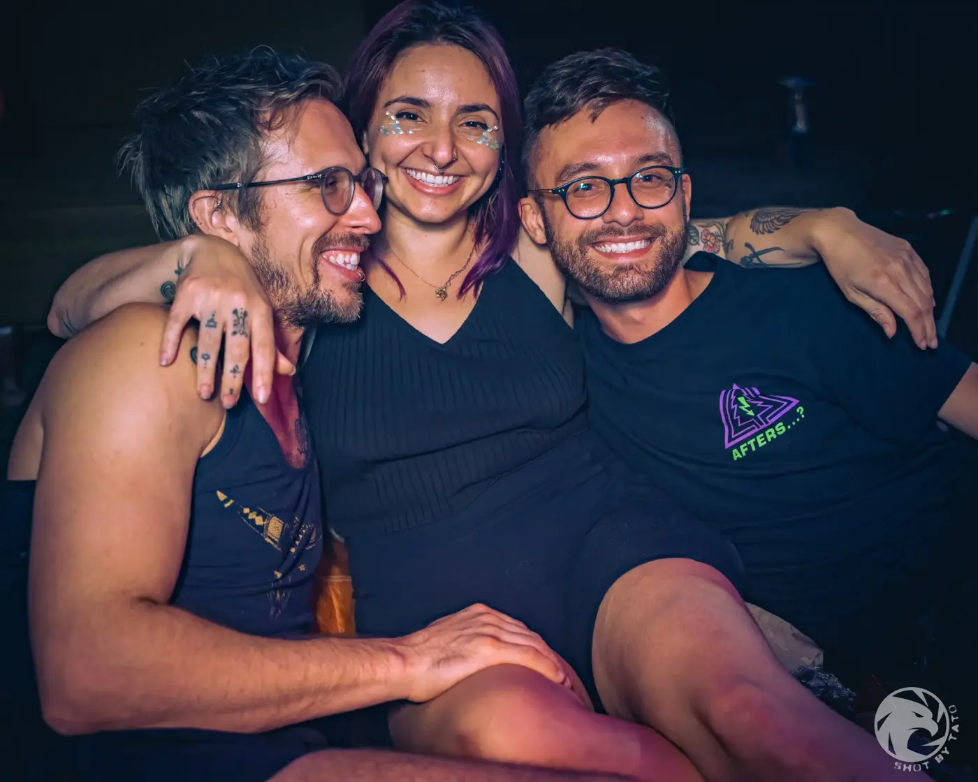 Three friends smiling with their arms around each other at a Pluto Events party