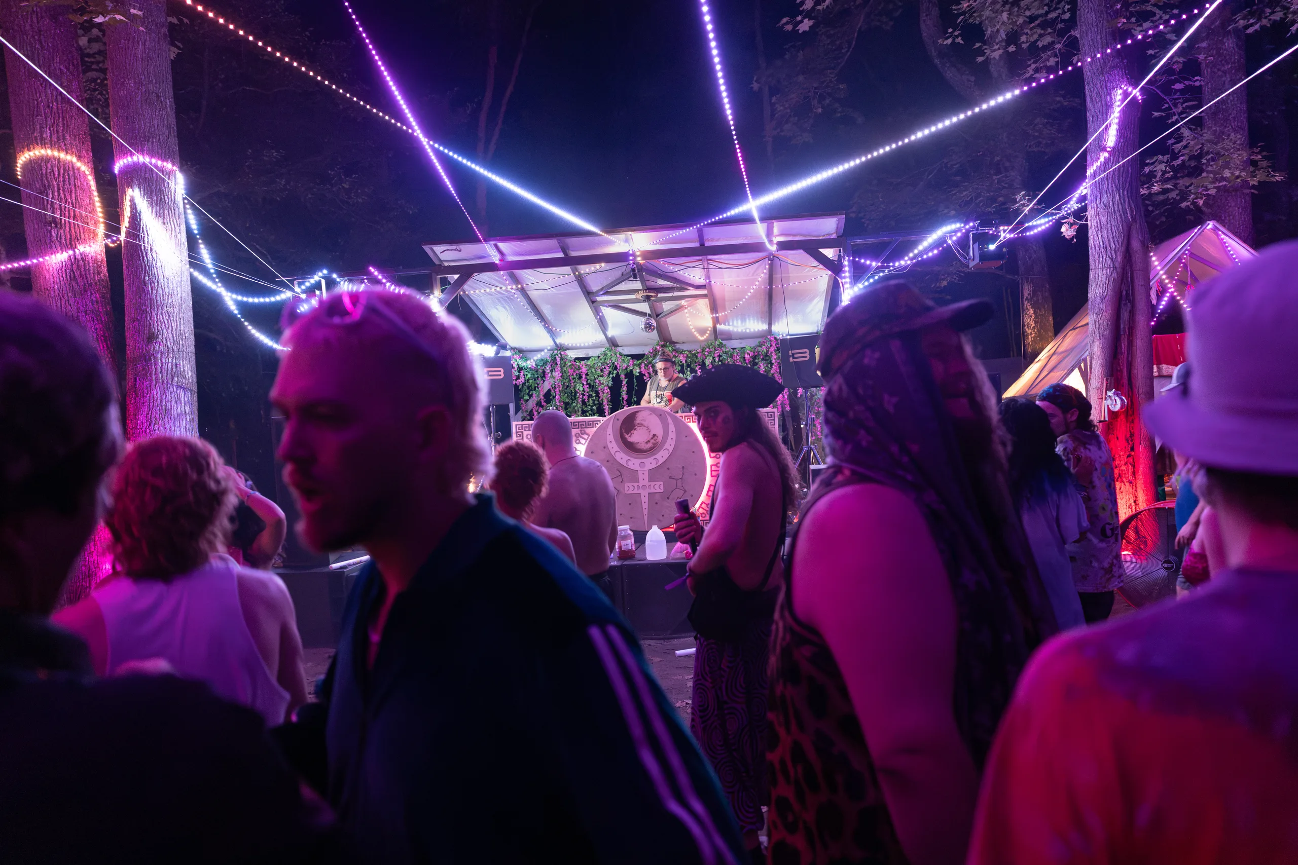 Attendees in colorful hats on the dance floor beneath purple lights at ManaFest 2026