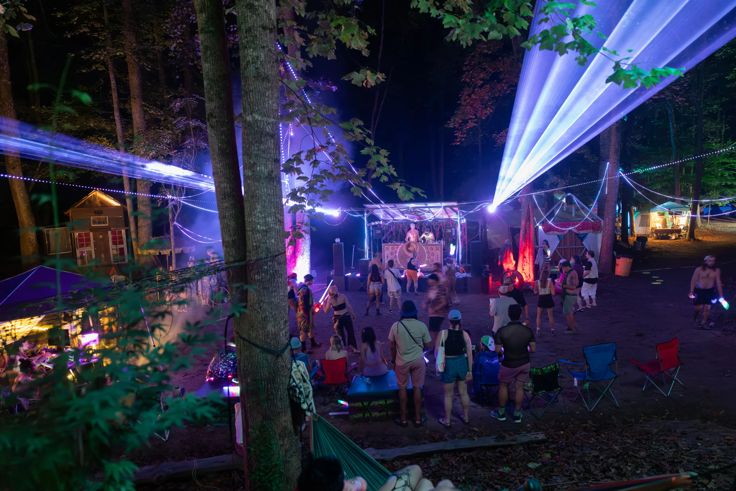Festivalgoers gathered around a forest stage under blue laser beams at ManaFest 2026